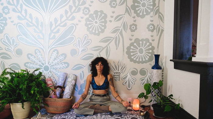 bohemian woman meditating in front of a mural